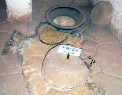 quern, stone mill ontp of a sheep skin, with grains nearby