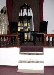 a lady in traditional attire standing by the curtained door overlooking the hall