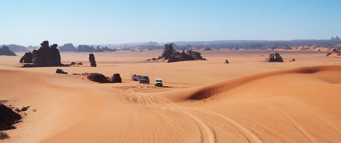 cars among the rocks and the endless sand dunes of the sahara