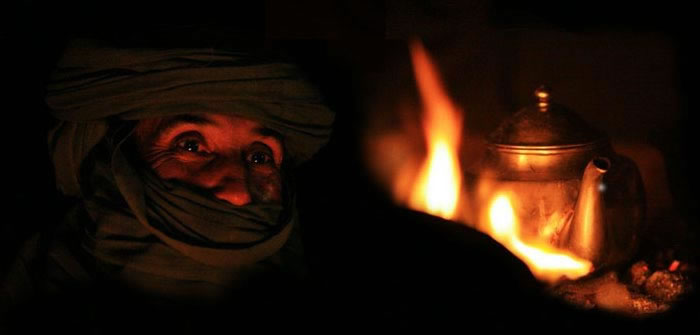 tuareg at night and a tea pot on fire in total darkness